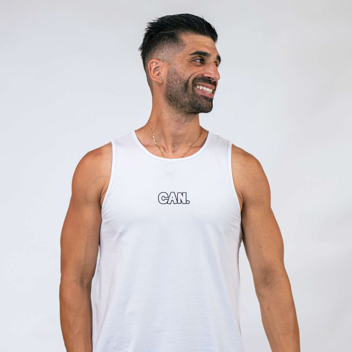 Man wearing a white CAN. Syndicate Athletic Tank with 'CAN.' text on a plain background