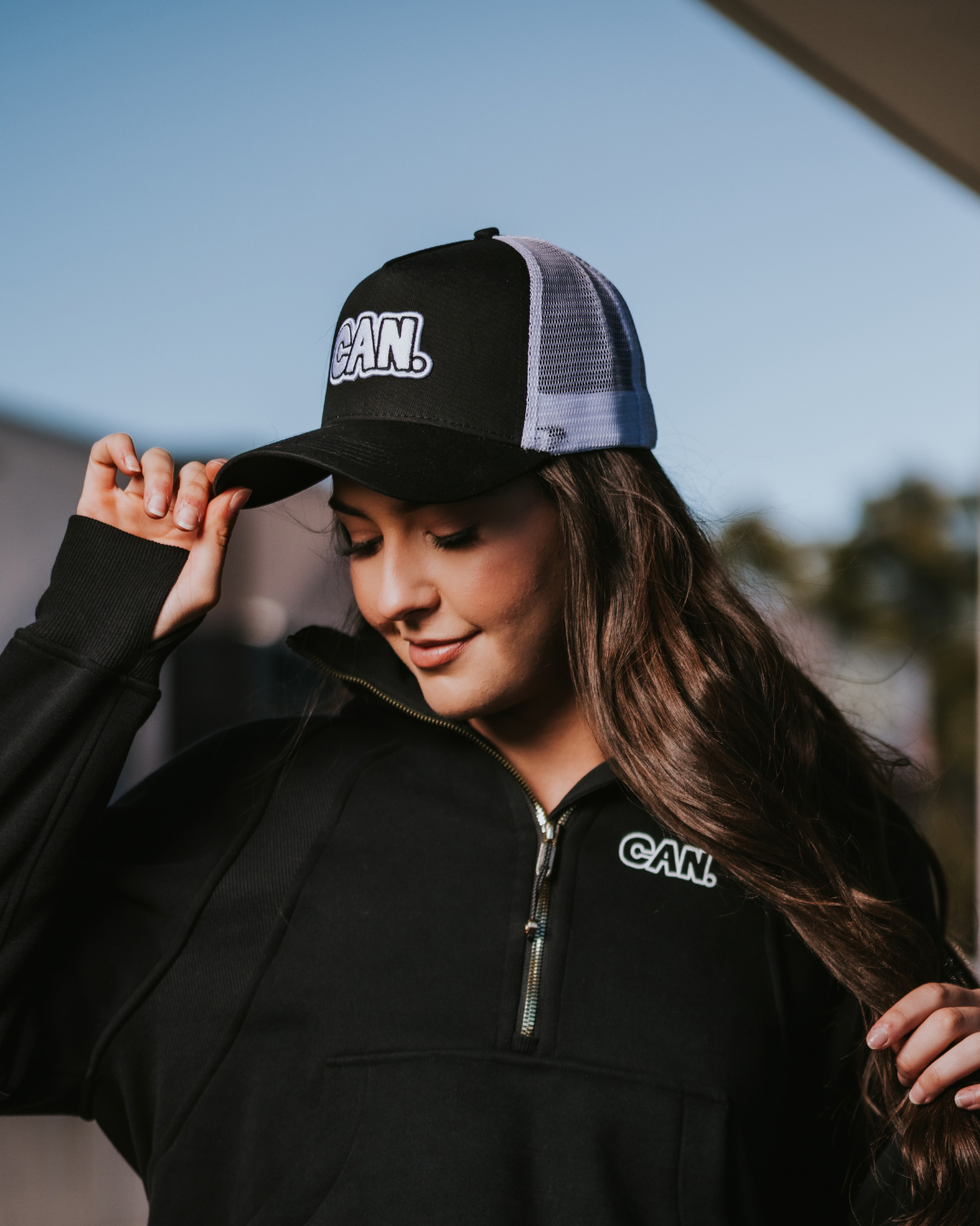 Model wearing a Can. Syndicate Cropped Zip Jumper and a black CAN. Classic Trucker Cap. 