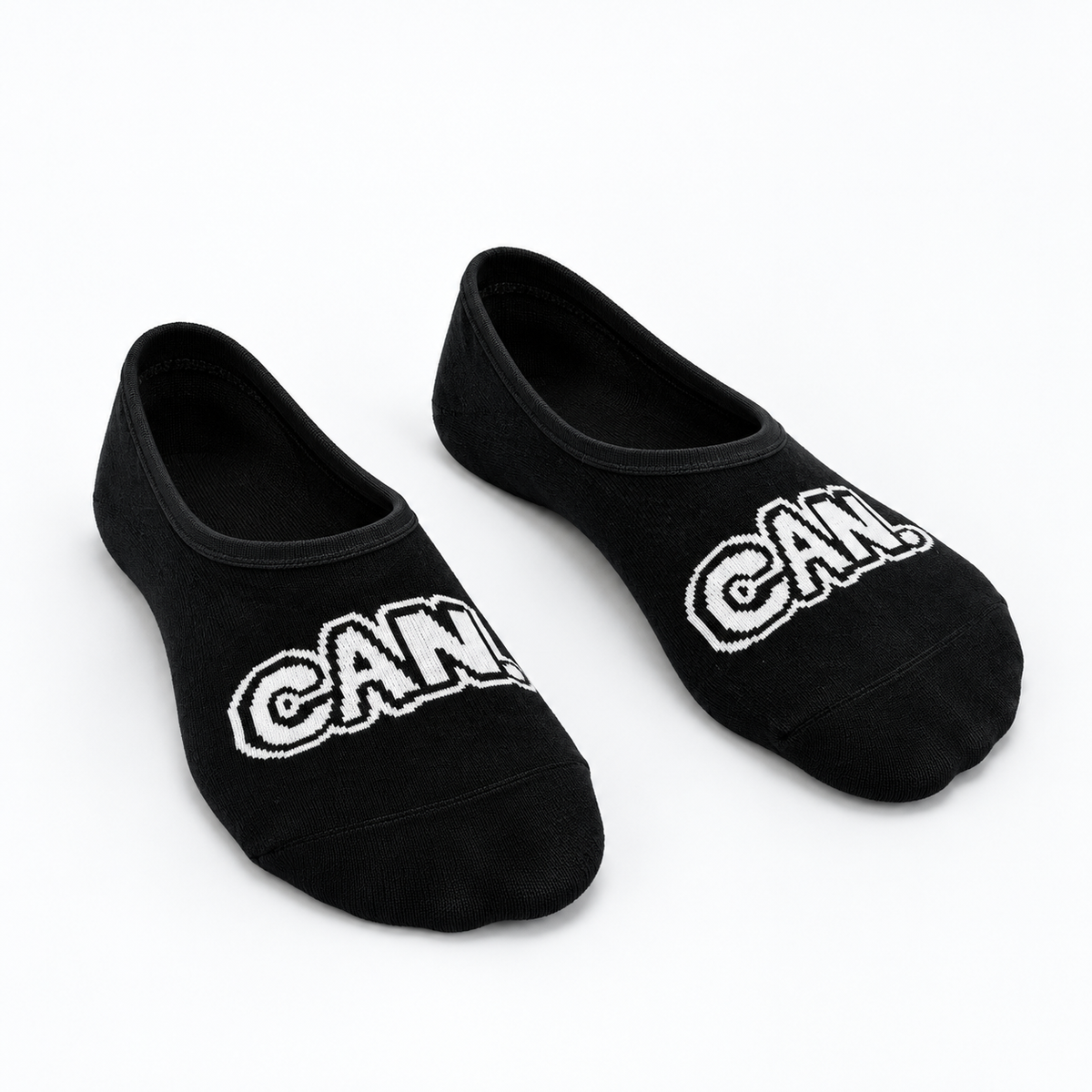 A pair of black low-cut Can. Syndicate No Show Socks with 'CAN' written across the toes in white outlined lettering, displayed on a clean white background.