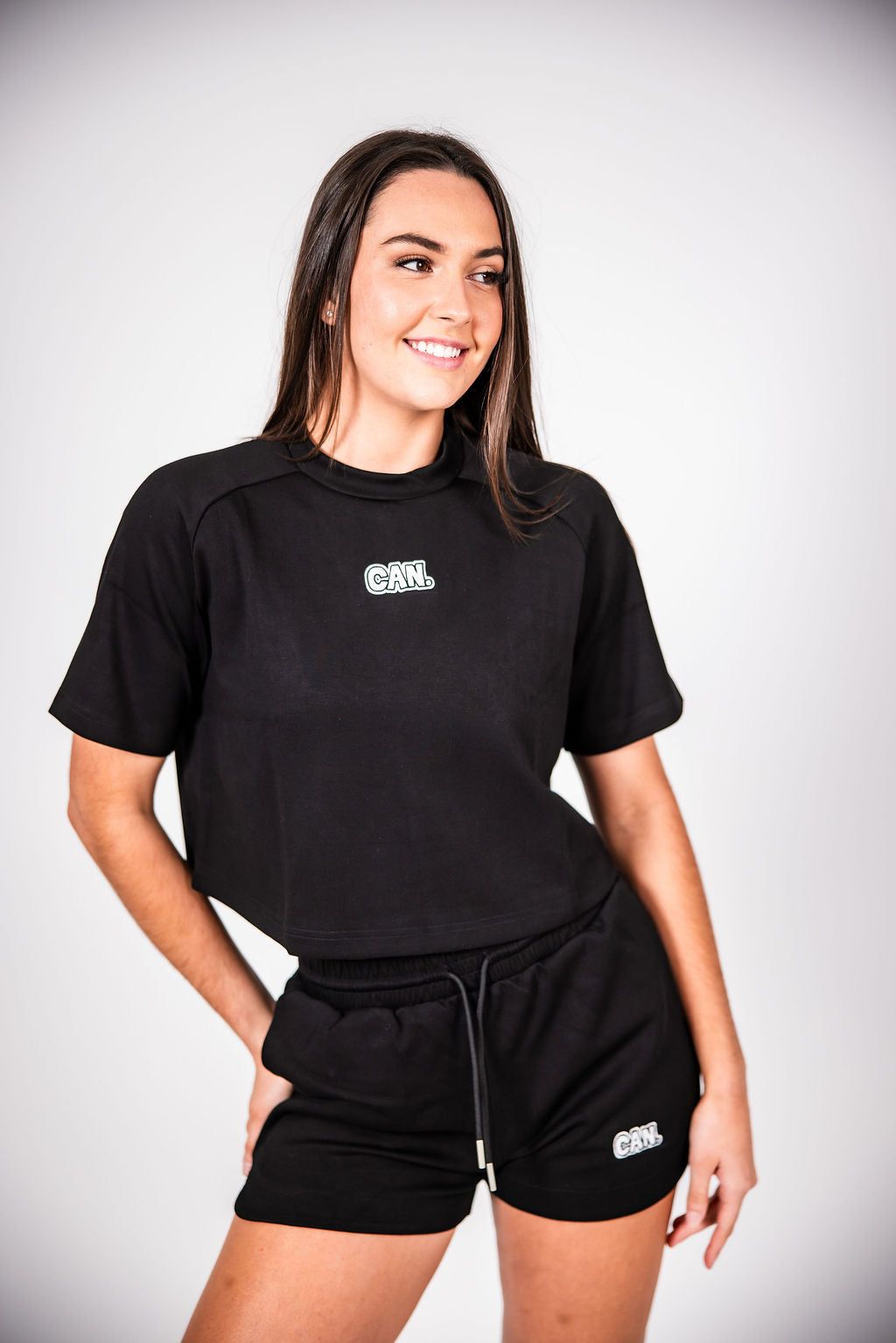 Woman wearing black Can. Syndicate Comfort Shorts and a Can. Syndicate Comfort Cropped Tee against a light grey background