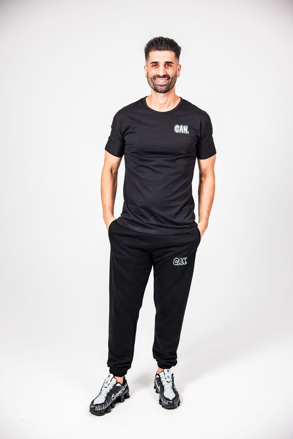 James Webb wearing a black CAN. Syndicate Men's Fitted Tee with 'CAN' branding on a white background
