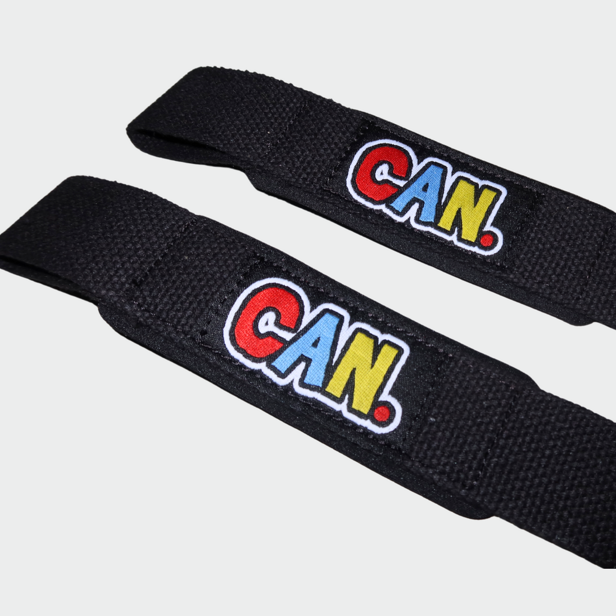 Close up of a red, blue and yellow CAN. logo on a black pair of CAN. Syndicate lifting straps. 