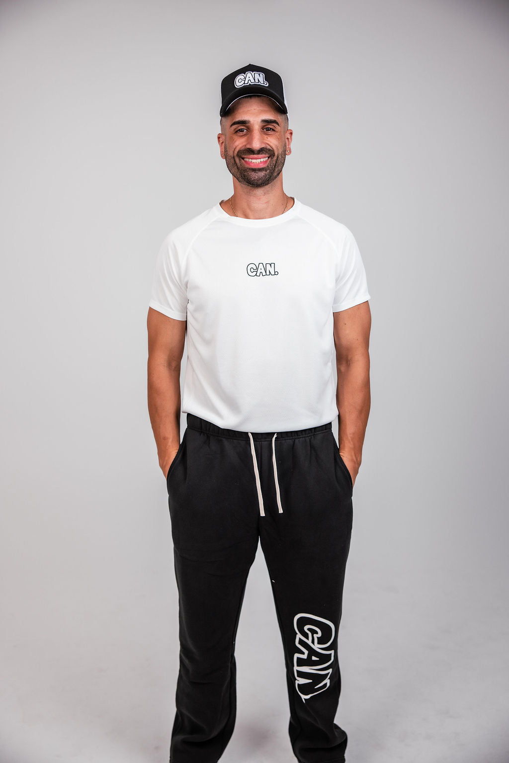 James Webb modelling Comfort Baggy Track Pants and Men's Athletic Tee, both with an outlined 'CAN.' logo. 