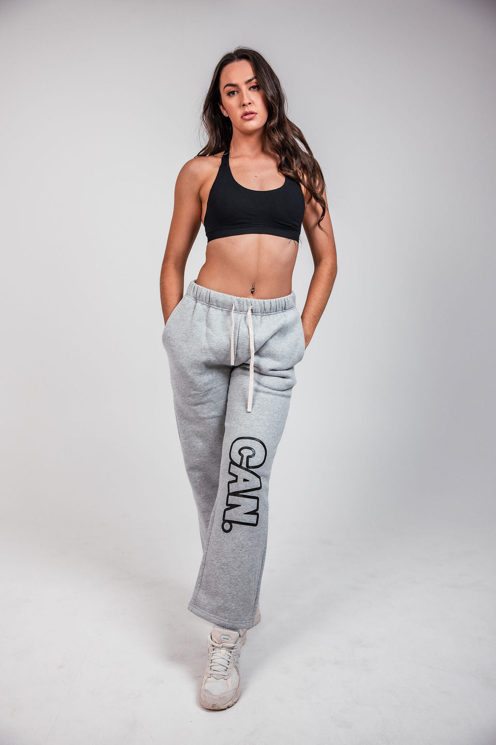 A woman modelling grey CAN. Syndicate Comfort Baggy Track Pants and a black CAN. contour sculpt crop top for CAN. syndicate in opus media group Penrith 