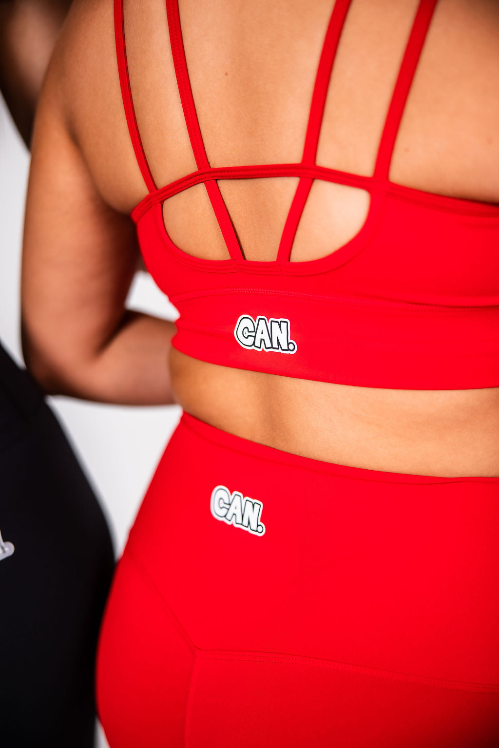 Close-up of a woman wearing red Can. Syndicate Forge Full Length Leggings and a red Can. Syndicate Forge Crop Top in front of a light grey background