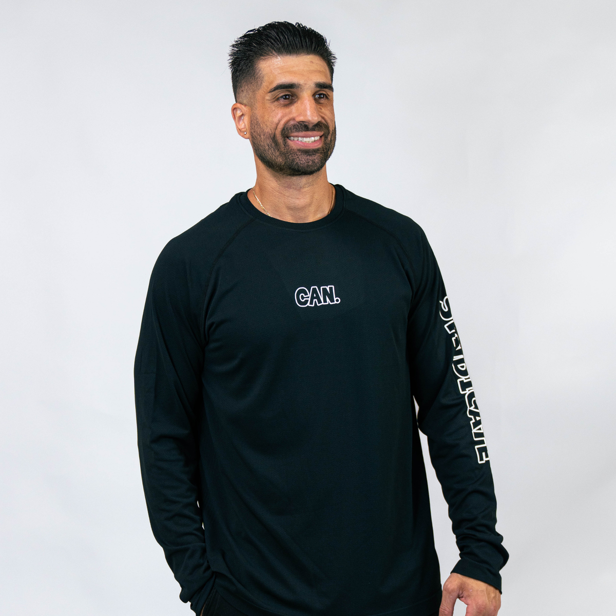 Man wearing a black CAN. Syndicate Men's Long Sleeve Athletic Tee  with text on a white background