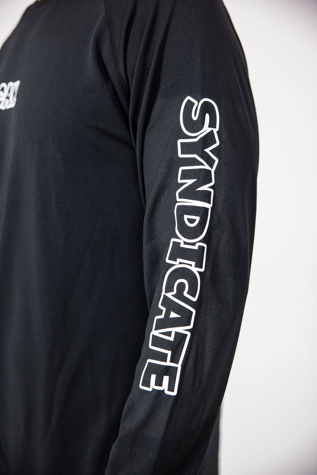 Close up of the sleeve of the CAN. Syndicate Men's Long Sleeve Athletic Tee that reads 'SYNDICATE'