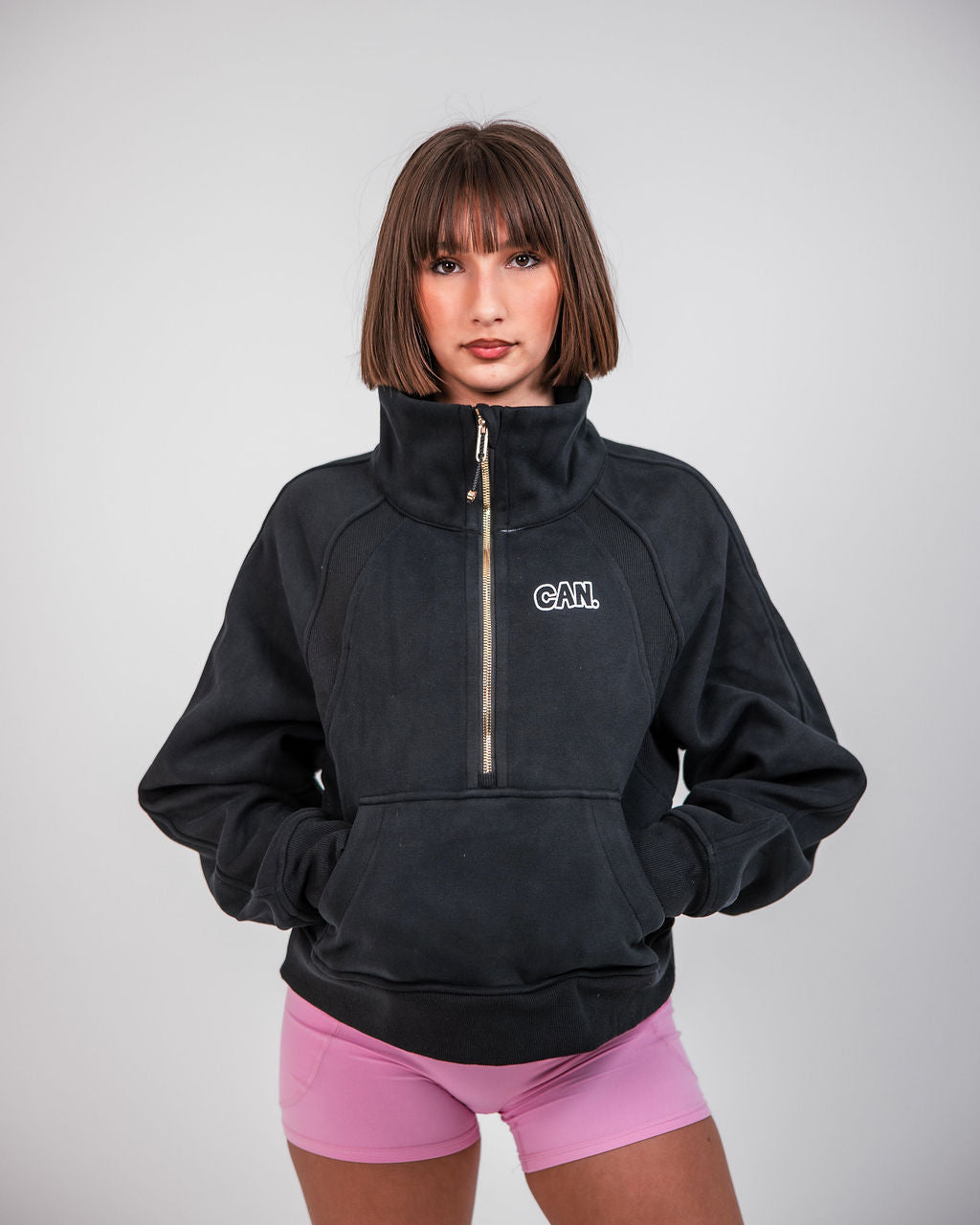 woman wearing a CAN. Syndicate cropped zip jumper and pink bike shorts